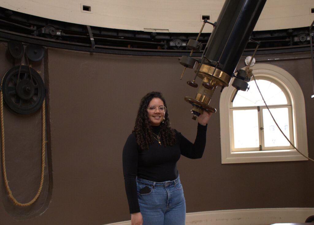 Marbely Micolta, a doctoral student at the University of Michigan, poses with the Fitz Refracting Telescope at the Detroit Observatory in Ann Arbor, Michigan. Image credit: Vaishnav Rao
