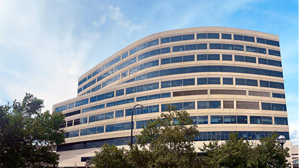 A large hospital exterior with a blue sky and trees in the foreground