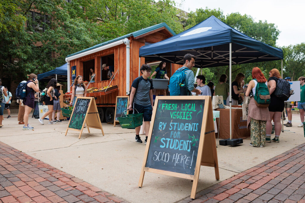 Students shop for locally-grown produce at the opening of the Campus Farm’s Mobile Food Stand. Image courtesy: Michigan Commons